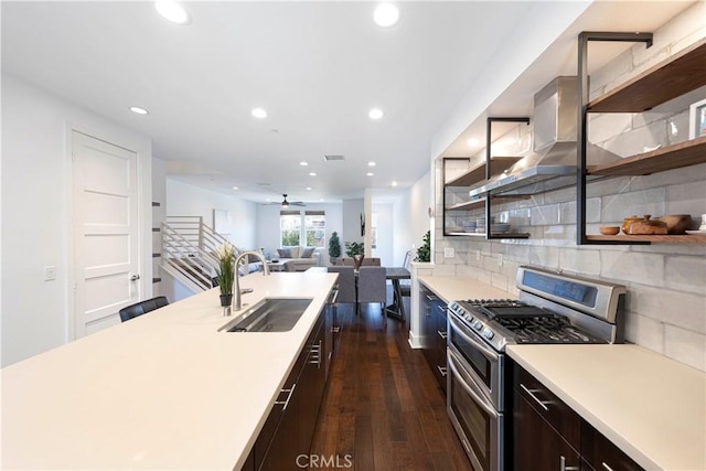 kitchen featuring a sink, open shelves, wall chimney range hood, and range with two ovens