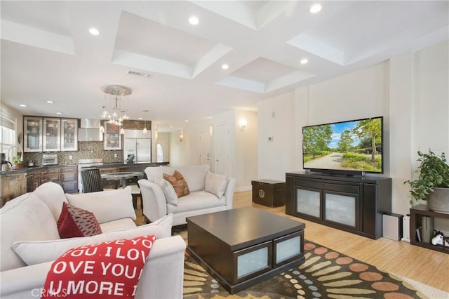 living area with visible vents, recessed lighting, light wood-style flooring, an inviting chandelier, and coffered ceiling