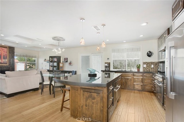 kitchen featuring a kitchen island, open floor plan, a breakfast bar area, light wood-style flooring, and a sink