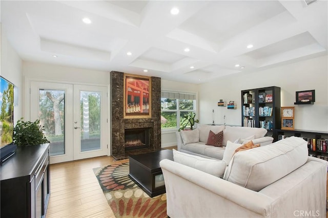 living room featuring recessed lighting, french doors, a fireplace, light wood-style floors, and coffered ceiling