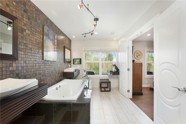 full bath featuring tile patterned flooring, baseboards, two vanities, a whirlpool tub, and tile walls