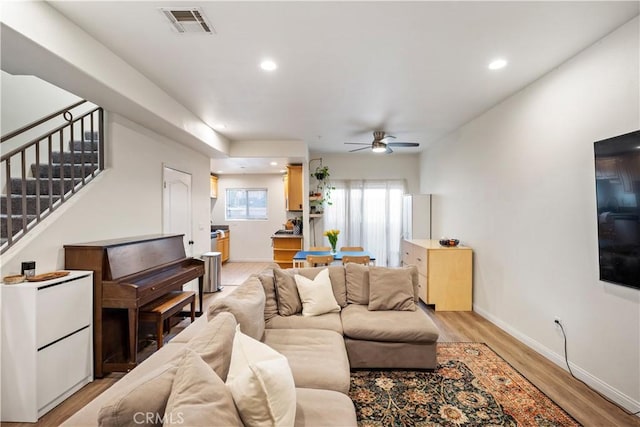 living room with light wood finished floors, visible vents, baseboards, stairway, and recessed lighting