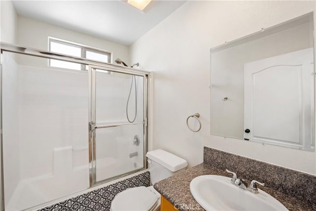 bathroom with toilet, vanity, and a shower with shower door