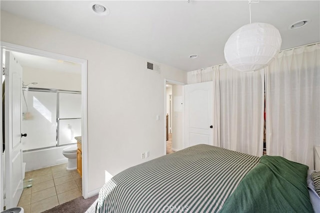 bedroom featuring light tile patterned floors, visible vents, ensuite bathroom, and light carpet