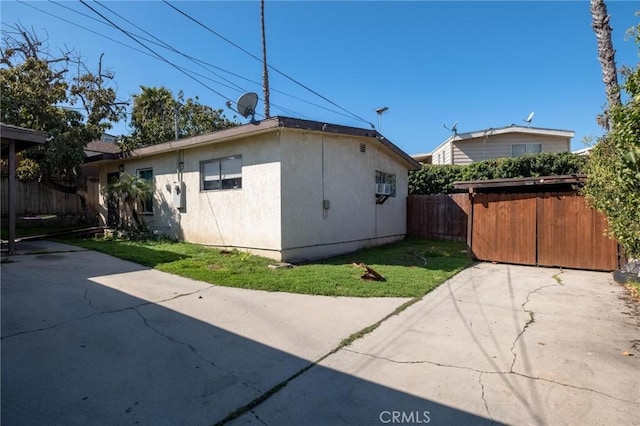 view of property exterior featuring stucco siding, a yard, and fence