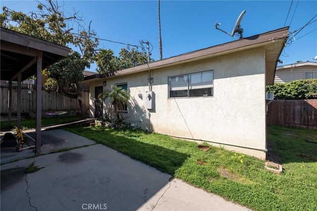 rear view of property with a yard, stucco siding, a patio, and fence