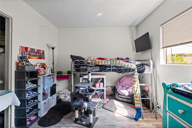 bedroom with a textured ceiling and wood finished floors