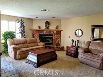 living room featuring a brick fireplace, visible vents, and a textured ceiling