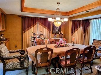 dining space with an inviting chandelier and a raised ceiling