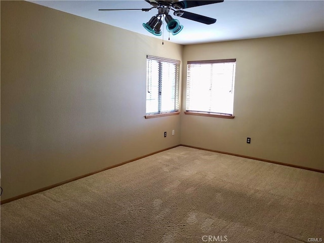 empty room with a ceiling fan, light colored carpet, and baseboards