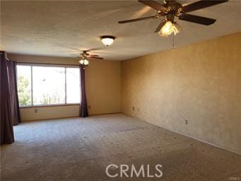 carpeted spare room with a ceiling fan