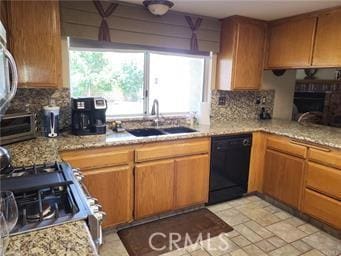 kitchen featuring a fireplace, a sink, decorative backsplash, gas range oven, and dishwasher