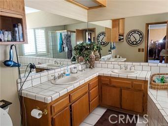 full bathroom featuring tile patterned flooring, double vanity, a shower with door, and a sink