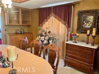 carpeted dining space with an inviting chandelier