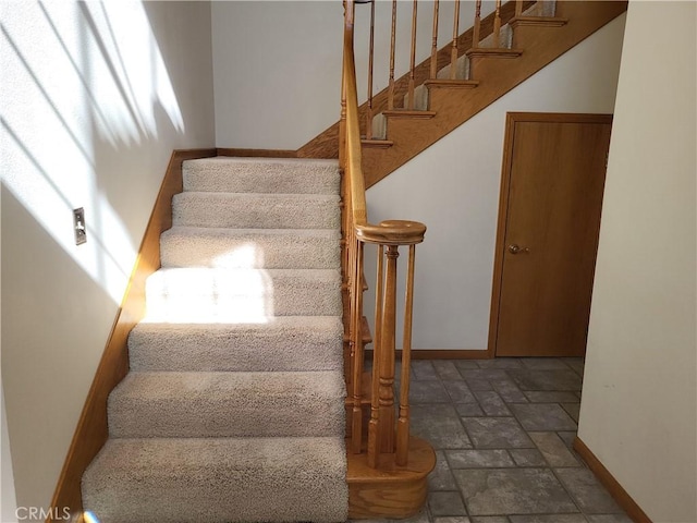 stairs with stone tile floors and baseboards