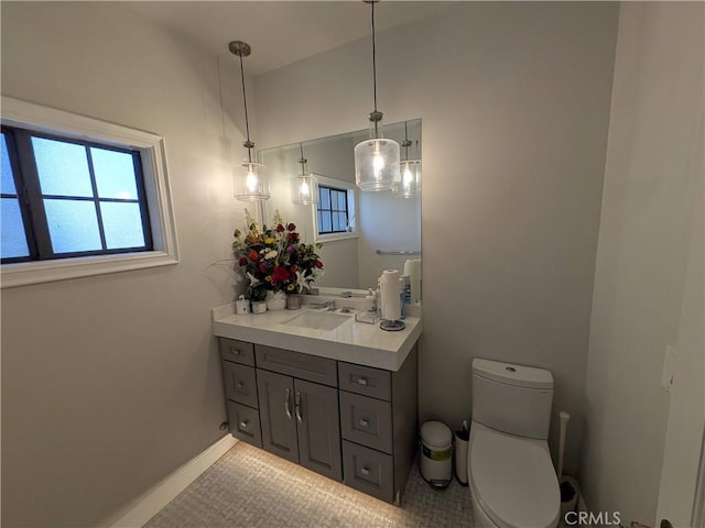 bathroom with vanity, toilet, a healthy amount of sunlight, and baseboards