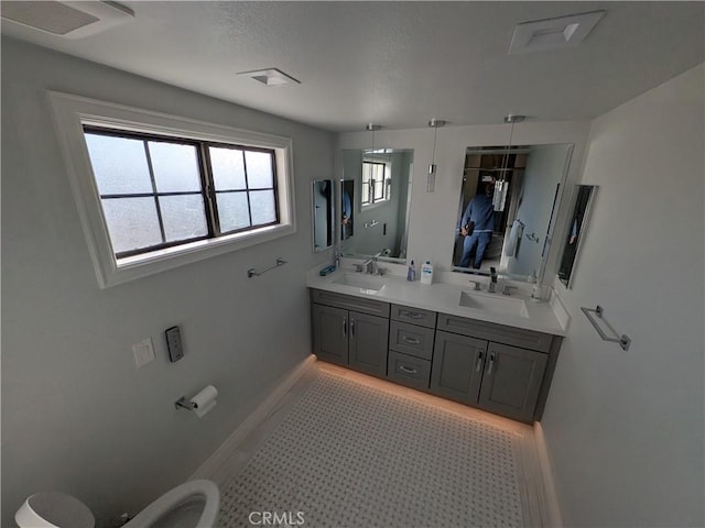 bathroom featuring a sink, baseboards, and double vanity