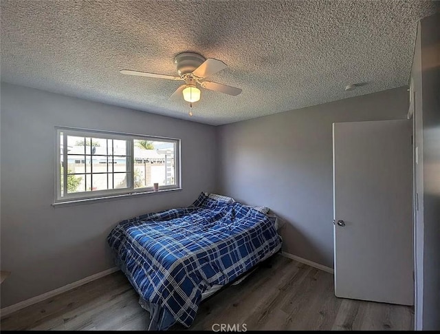 bedroom with ceiling fan, baseboards, a textured ceiling, and wood finished floors