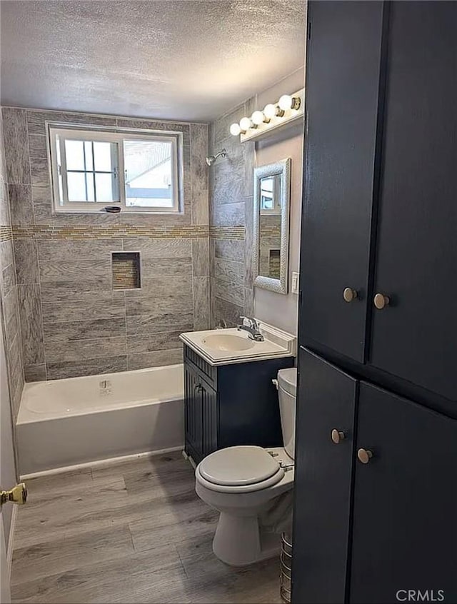 bathroom featuring toilet, shower / tub combination, a textured ceiling, wood finished floors, and vanity