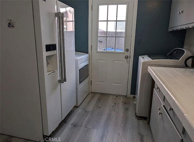 washroom with cabinet space, light wood-style flooring, and washer and clothes dryer