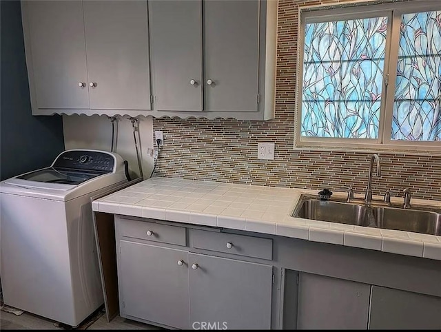 clothes washing area with a sink, a wealth of natural light, cabinet space, and washer / clothes dryer