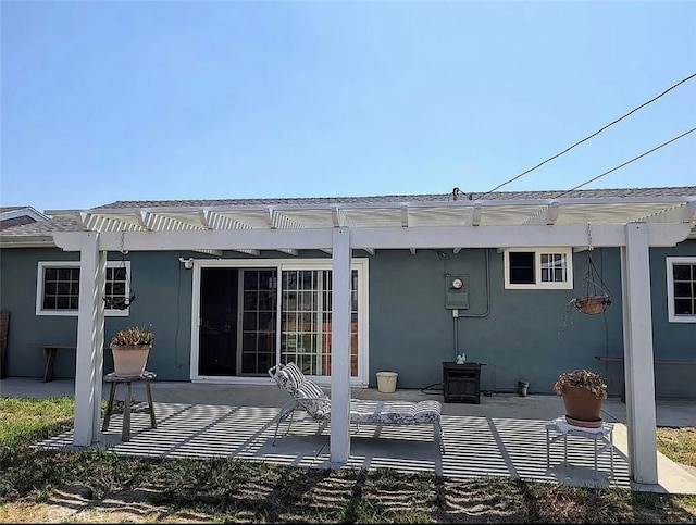 rear view of property featuring stucco siding, a patio, and a pergola