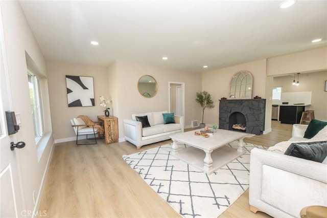 living room with a fireplace, recessed lighting, wood finished floors, and baseboards