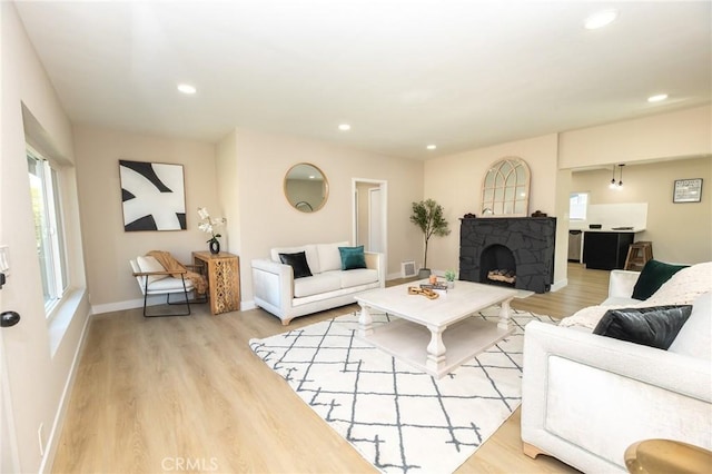 living room featuring visible vents, recessed lighting, a fireplace, light wood finished floors, and baseboards