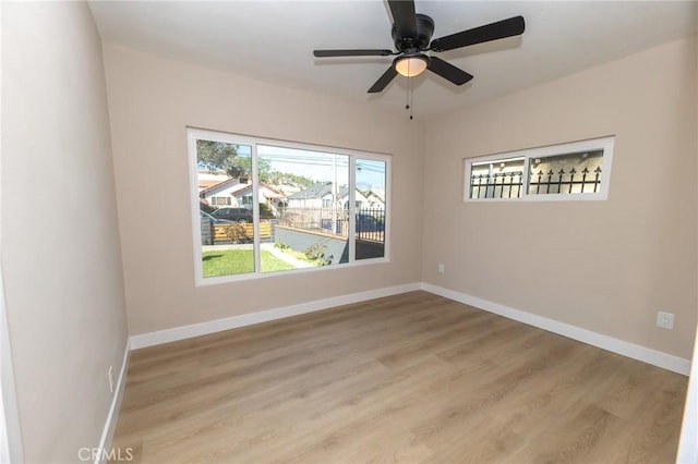 spare room with a ceiling fan, light wood-type flooring, and baseboards