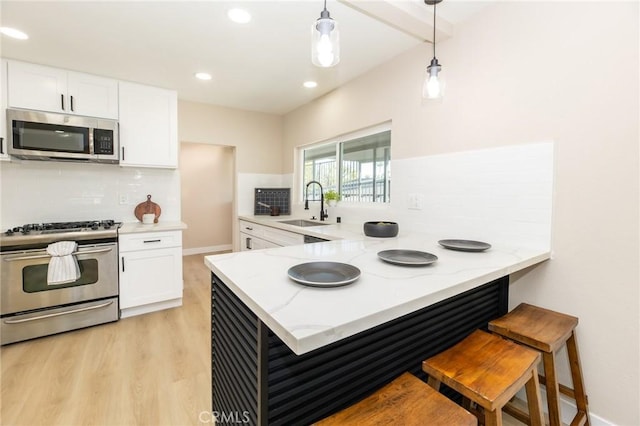 kitchen featuring light stone counters, white cabinets, stainless steel appliances, and a sink