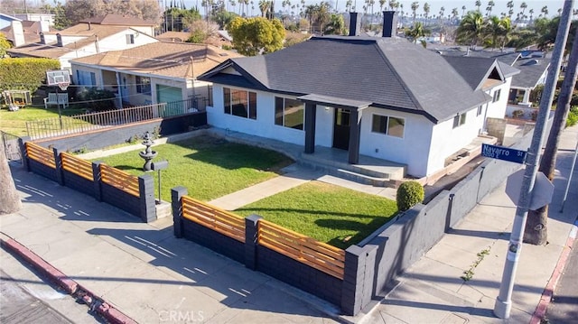 view of front of property with a residential view, stucco siding, a front lawn, and fence