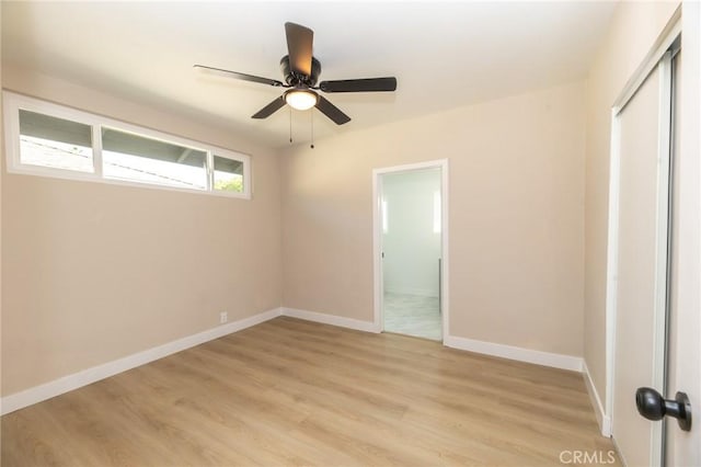 unfurnished bedroom featuring ceiling fan, a closet, baseboards, and light wood-style flooring