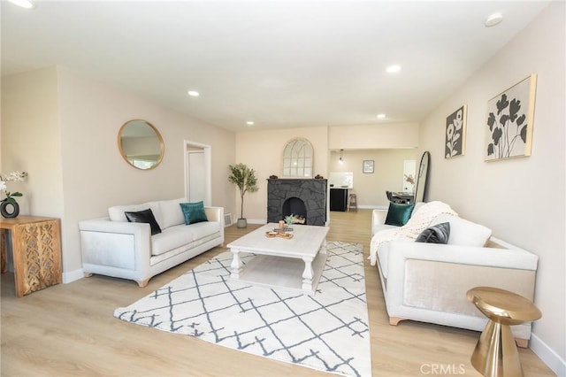 living room with recessed lighting, baseboards, light wood-style floors, and a stone fireplace