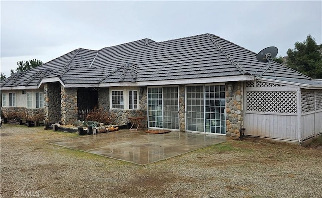 back of property featuring stone siding and a patio