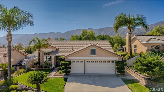 view of front of home with fence, driveway, a chimney, a garage, and a mountain view