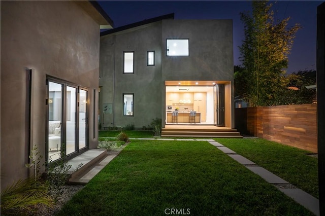 10943 Pickford Way, Culver City, CA 90230 - back of house at twilight featuring a lawn, fence, and stucco siding