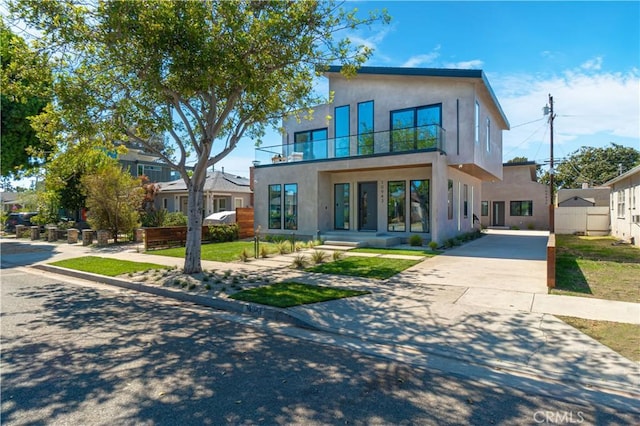 modern home with concrete driveway, a balcony, and stucco siding