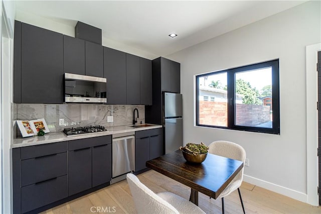 10943 Pickford Way, Culver City, CA 90230 - kitchen with decorative backsplash, light countertops, a sink, light wood finished floors, and appliances with stainless steel finishes