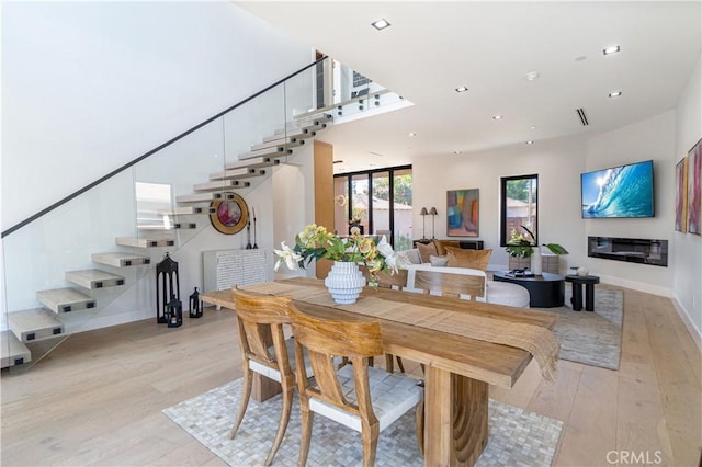 10943 Pickford Way, Culver City, CA 90230 - dining room with visible vents, stairs, light wood finished floors, a glass covered fireplace, and recessed lighting