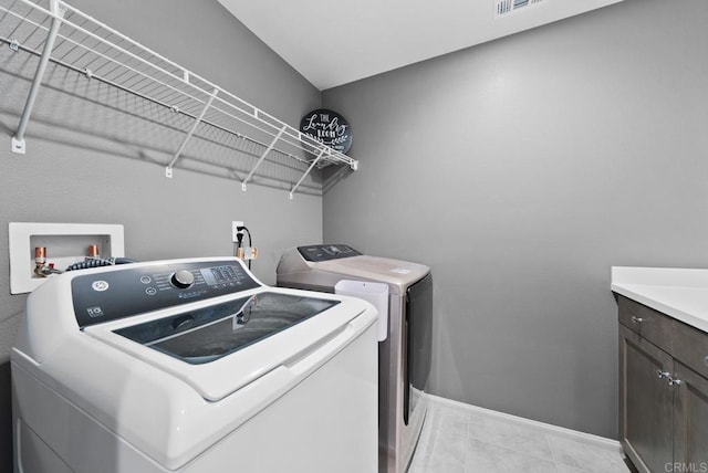 clothes washing area with cabinet space, light tile patterned floors, separate washer and dryer, and baseboards