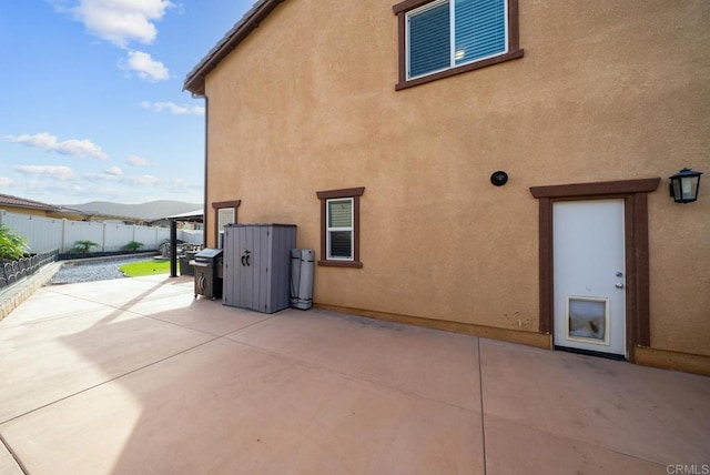 back of property with a patio area, stucco siding, a mountain view, and fence