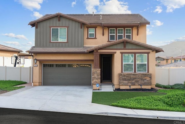 craftsman house featuring a tiled roof, board and batten siding, concrete driveway, and fence