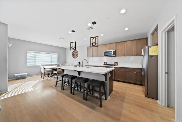 kitchen with light wood finished floors, visible vents, stainless steel appliances, and light countertops