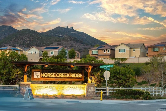 community / neighborhood sign featuring fence, a mountain view, and a residential view