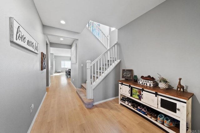 hall featuring stairway, recessed lighting, baseboards, and light wood-style floors