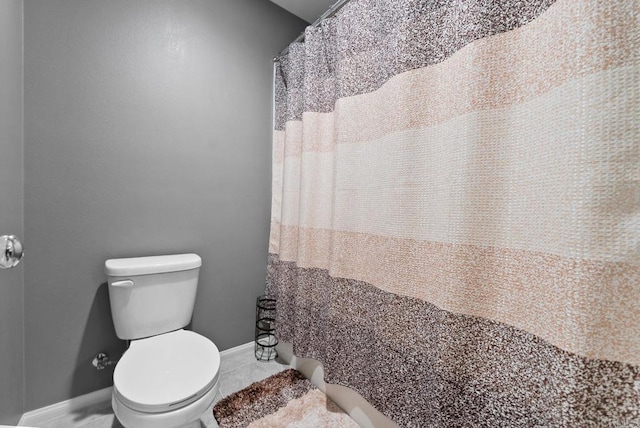 bathroom featuring tile patterned flooring, toilet, a shower with curtain, and baseboards