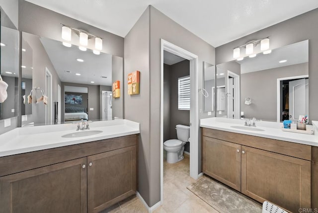 ensuite bathroom with tile patterned floors, ensuite bath, two vanities, and a sink