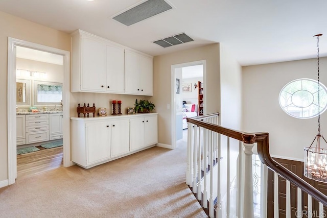 interior space with light carpet, visible vents, white cabinets, and an inviting chandelier