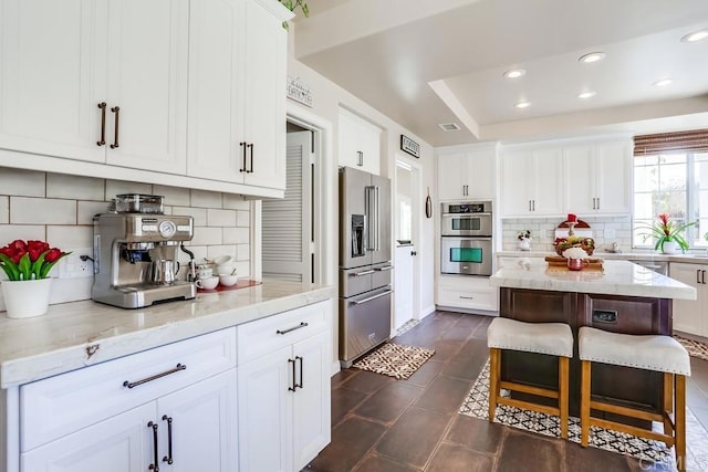 kitchen with tasteful backsplash, white cabinetry, recessed lighting, appliances with stainless steel finishes, and light stone countertops