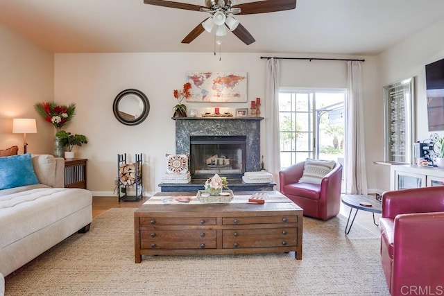 living area featuring a ceiling fan, baseboards, and a premium fireplace